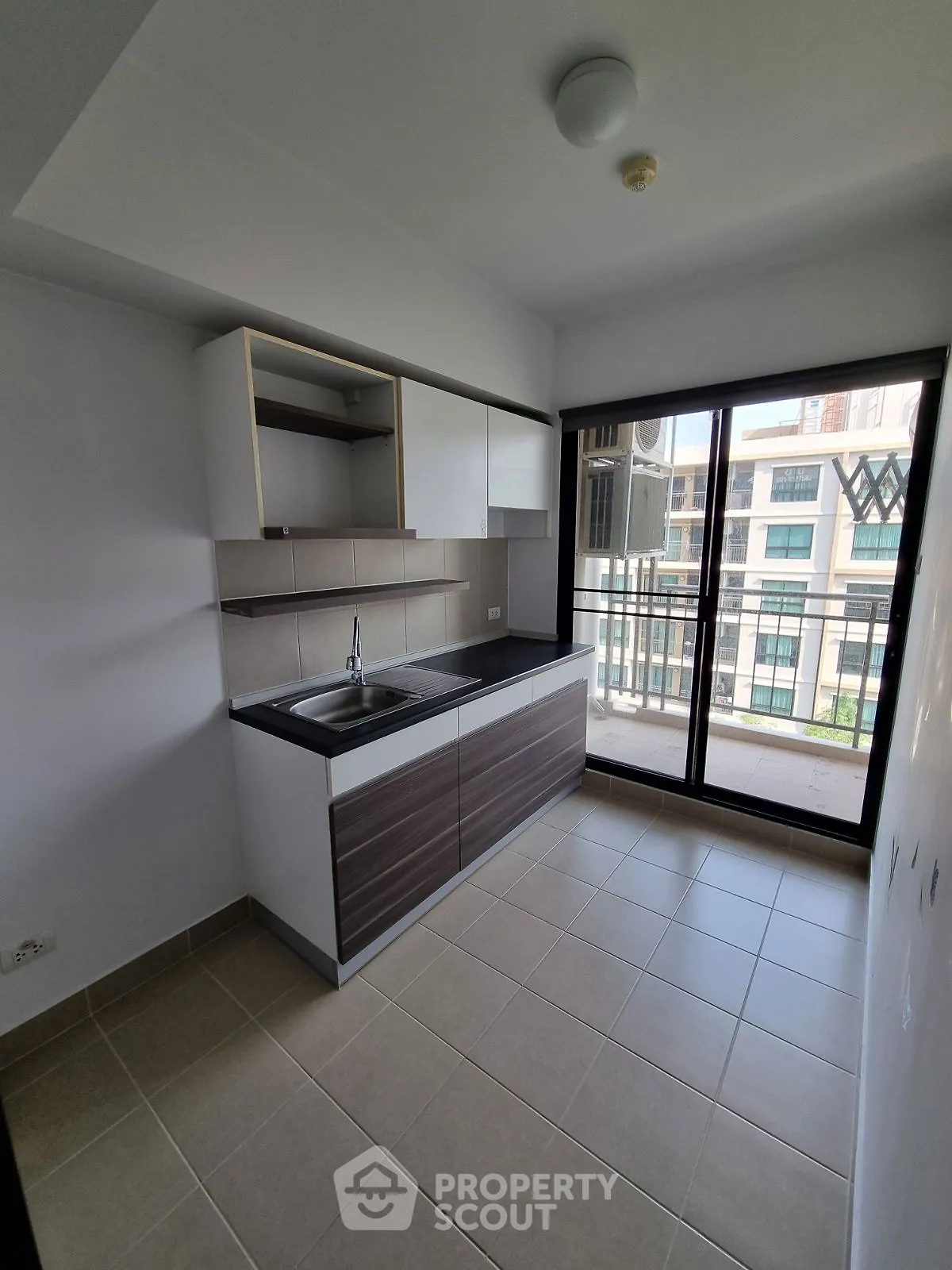 Modern kitchen with sleek cabinets and balcony view in a stylish apartment.