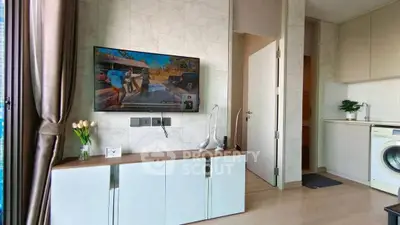 Modern living room with wall-mounted TV and washing machine in stylish apartment.