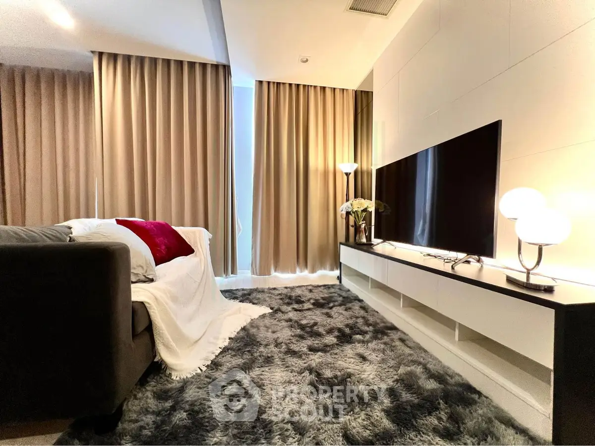 Cozy living room with plush rug, modern TV setup, and elegant lighting.