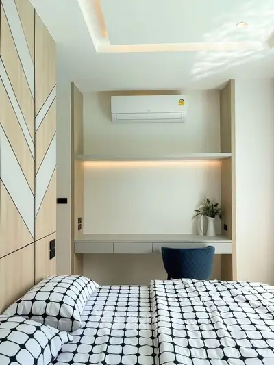 Modern bedroom with stylish decor and built-in study area, featuring air conditioning and contemporary design.