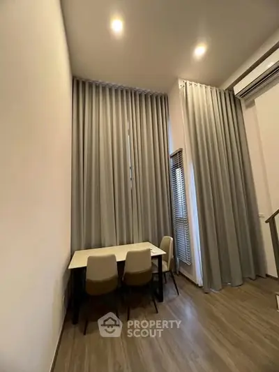 Modern dining area with high ceilings and elegant drapes in a stylish apartment.