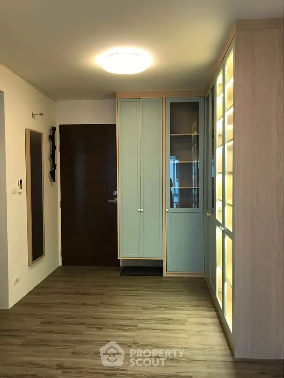Stylish entryway with modern wooden flooring and illuminated storage cabinets.