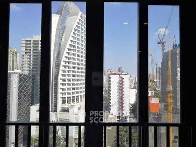 Stunning cityscape view from high-rise building window showcasing modern architecture and construction cranes.