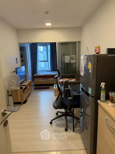 Modern studio apartment with open layout, featuring a cozy living area, compact kitchen, and large window for natural light.