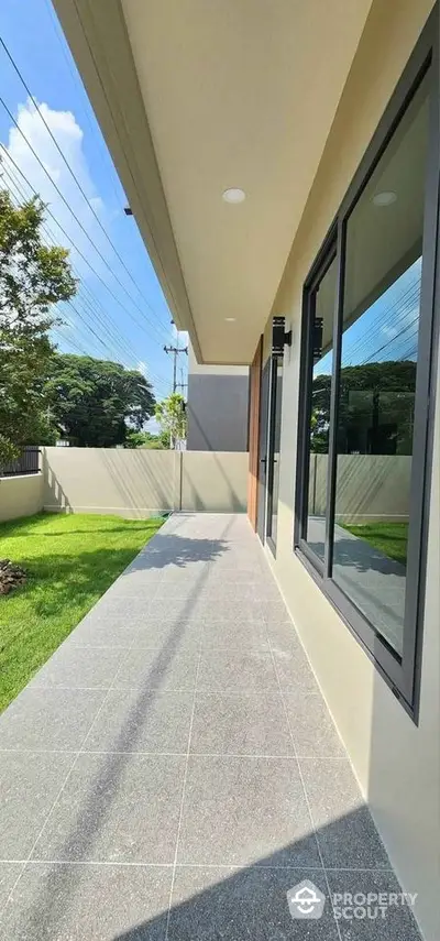 Modern exterior view with spacious tiled walkway and lush green lawn