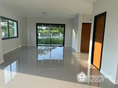 Spacious and sunlit living room with gleaming tiled floors, large windows offering a serene garden view, and modern design ready for customization.