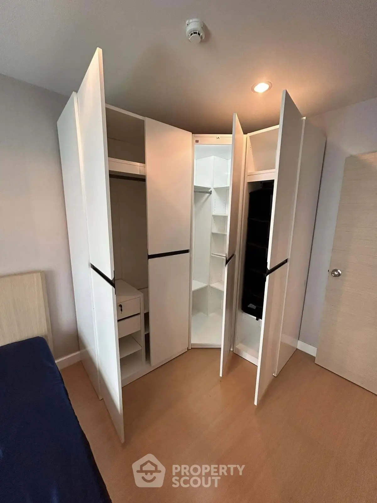 Spacious modern bedroom with innovative corner wardrobe design and sleek wooden flooring.
