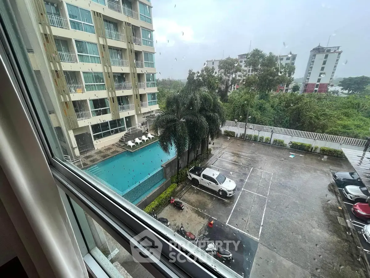 Stunning view from window overlooking pool and parking area in modern apartment complex.