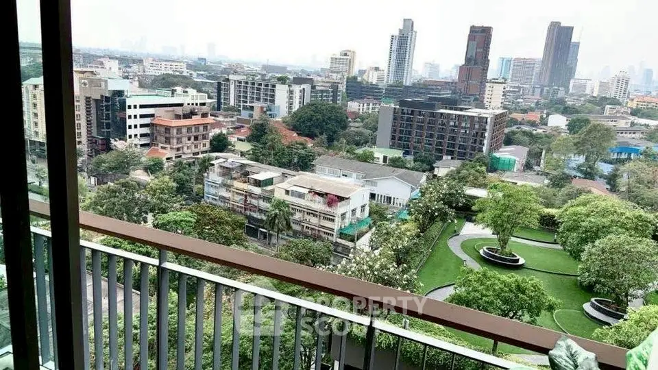 Stunning cityscape view from a high-rise balcony overlooking lush greenery and modern buildings.