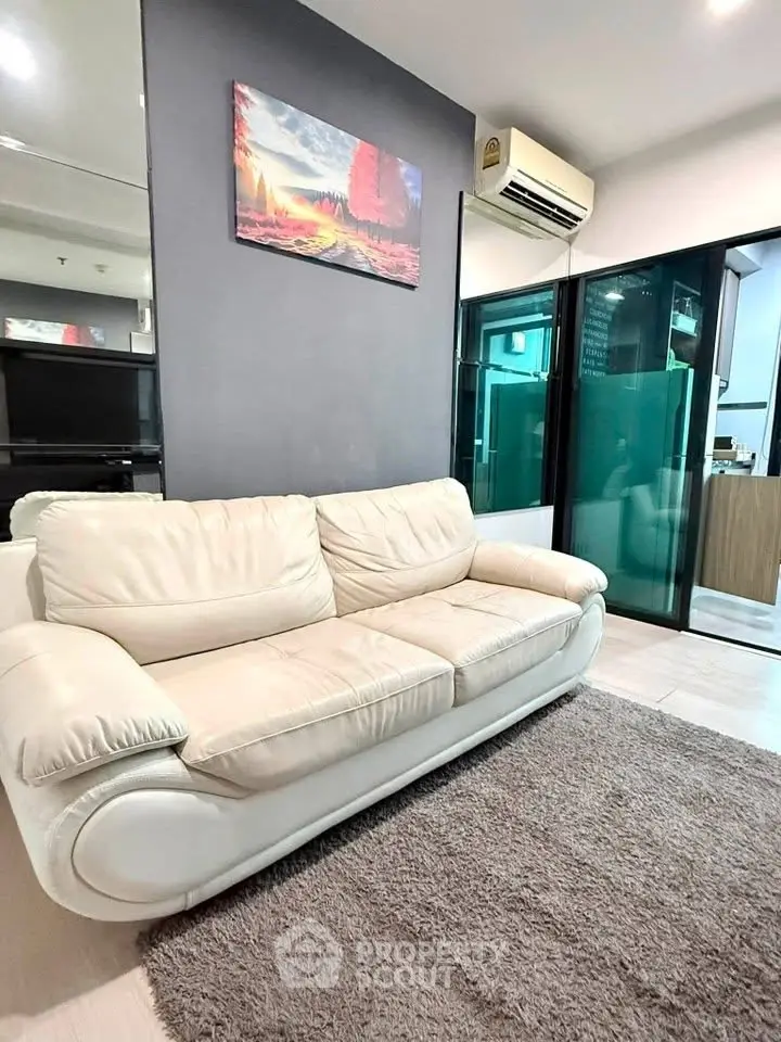 Modern living room with stylish white sofa and air conditioning, featuring sleek glass doors and contemporary decor.