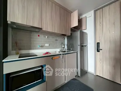 Modern compact kitchen with sleek cabinetry and stainless steel appliances in a stylish apartment.