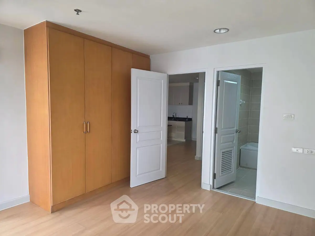 Spacious bedroom with wooden wardrobe and ensuite bathroom in modern apartment