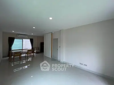 Spacious modern living room with dining area and large window, perfect for family gatherings.