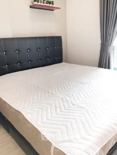 Cozy bedroom with stylish headboard and natural light, perfect for relaxation.