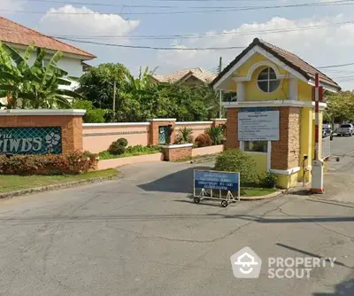 Charming gated community entrance with lush greenery and welcoming signage