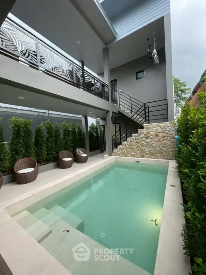 Luxurious modern home with private pool and stylish outdoor seating area, perfect for relaxation.