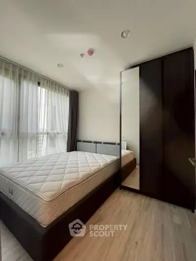 Modern bedroom with large window and sleek wardrobe in a stylish apartment.