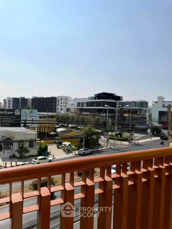 Urban view from balcony overlooking cityscape with modern buildings and clear sky.