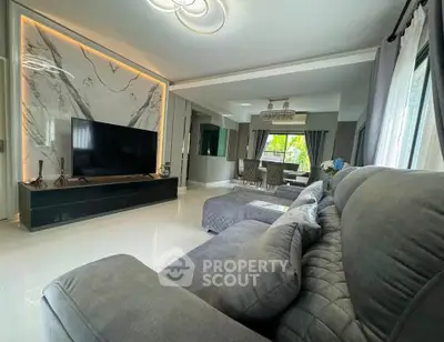 Luxurious living room with modern decor and large TV, perfect for relaxation and entertainment.