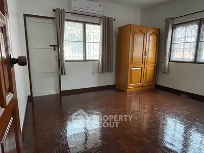 Spacious bedroom with wooden wardrobe and polished floors in a cozy home.