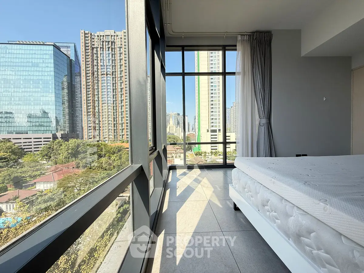 Spacious bedroom with floor-to-ceiling windows offering stunning city views
