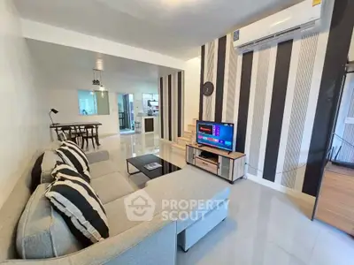 Modern living room with stylish decor and open layout, featuring a cozy sofa and wall-mounted air conditioner.