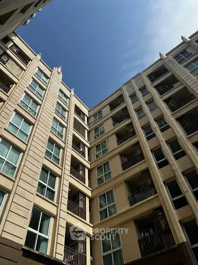 Stunning view of modern apartment building exterior with clear blue sky backdrop.