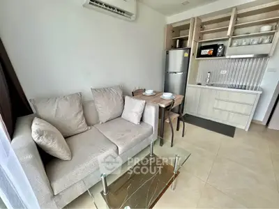 Modern compact living area with kitchenette, cozy sofa, and dining table in a stylish apartment.