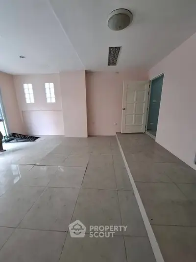 Spacious empty room with tiled flooring and natural light, ideal for customization.