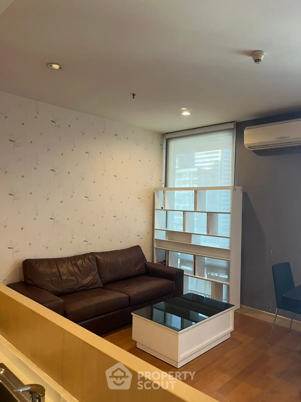 Cozy living room with leather sofa and modern shelving unit in a stylish apartment.