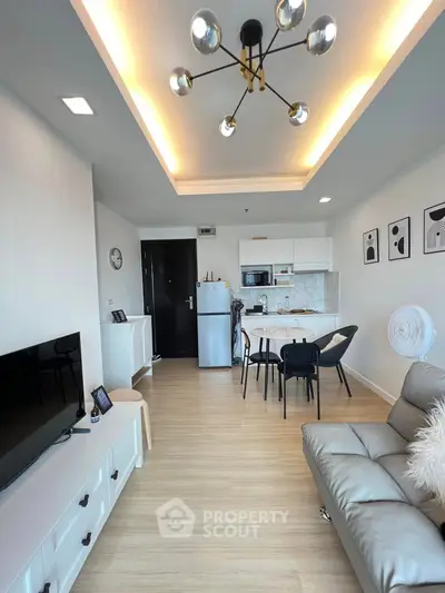 Modern living room with open kitchen, stylish lighting, and cozy seating area