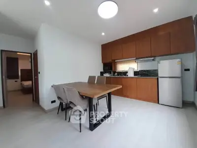 Modern kitchen with wooden cabinets and dining area in open layout apartment.
