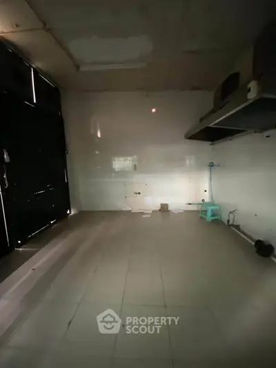 Spacious empty kitchen with tiled floor and wall, ready for customization.