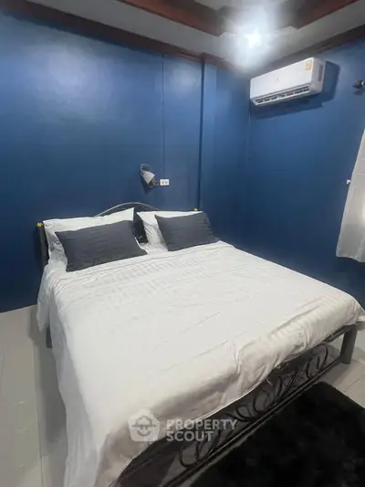 Cozy bedroom with modern air conditioning and stylish blue walls, perfect for restful nights.