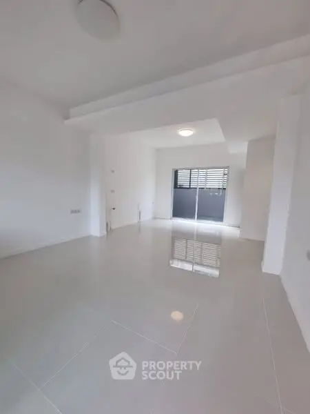 Spacious modern living room with sleek white tiles and natural light.