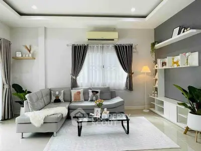 Modern living room with stylish decor, featuring a cozy gray sectional sofa, elegant curtains, and ambient lighting.