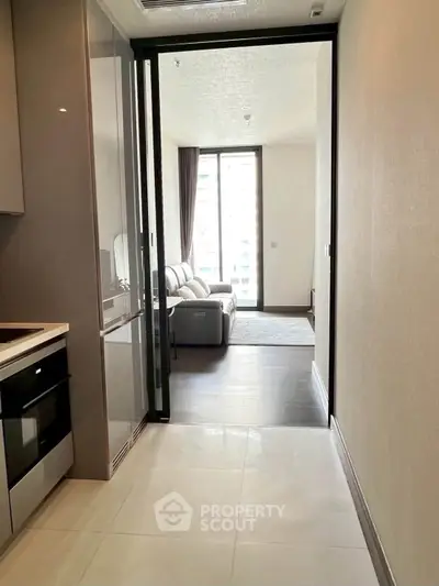 Modern apartment interior with sleek kitchen and cozy living room, featuring large windows for natural light.