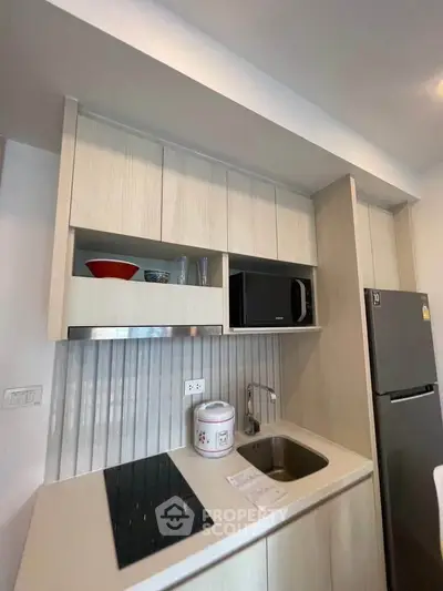 Modern kitchen with sleek cabinetry, built-in microwave, and compact fridge in a stylish apartment.