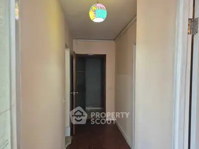 Charming hallway with wooden flooring and colorful ceiling light in cozy apartment.