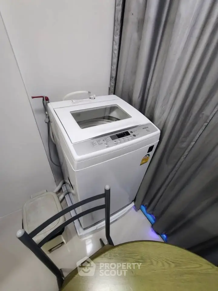 Compact laundry area with top-load washing machine and modern decor