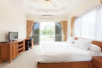 Spacious bedroom with balcony and natural light, featuring elegant wooden furniture and serene garden view.
