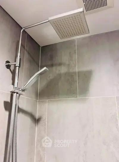 Modern bathroom with sleek showerhead and tiled walls, perfect for a contemporary home.