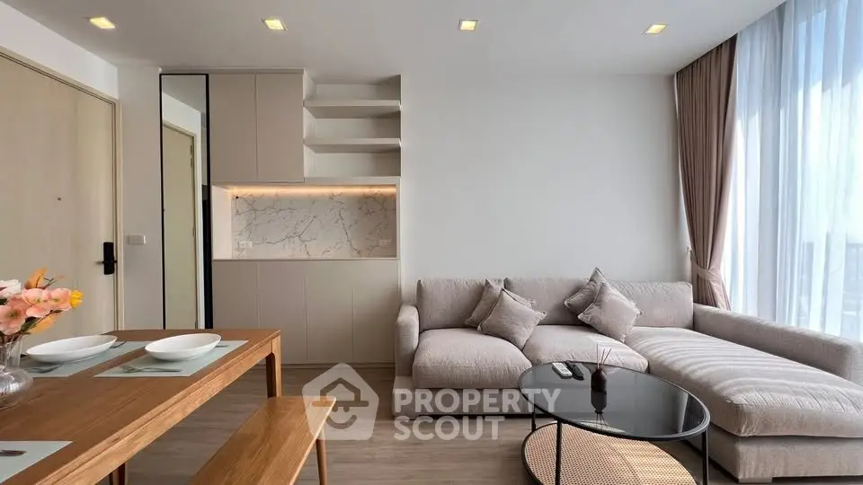 Modern living room with cozy sectional sofa and elegant dining area, featuring floor-to-ceiling windows and stylish decor.