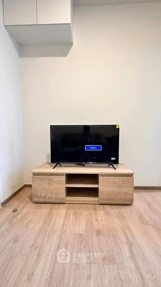 Modern living room with sleek TV stand and flat-screen TV on wooden flooring.