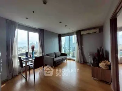 Spacious living room with city view and modern furnishings in high-rise apartment.