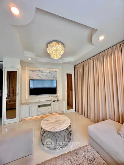 Luxurious living room with elegant chandelier and modern decor, featuring a marble coffee table and plush seating.