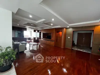 Spacious living room with wooden flooring and modern ceiling design, perfect for family gatherings.