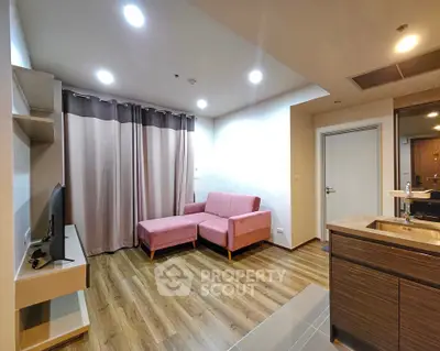 Modern living room with pink sofa, wooden flooring, and open kitchen layout
