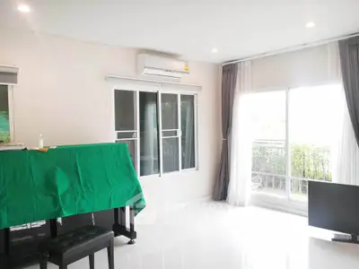 Bright living room with large windows and balcony access, featuring modern decor and air conditioning.