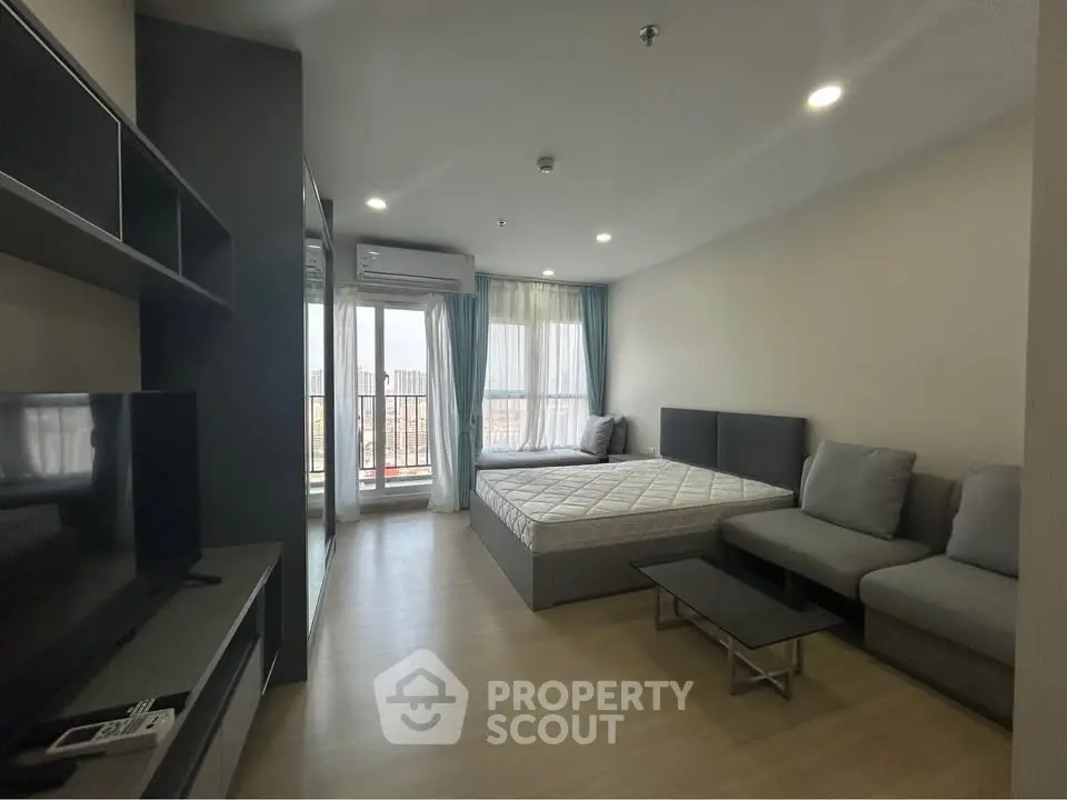Modern studio apartment with cozy living area and large windows for natural light.
